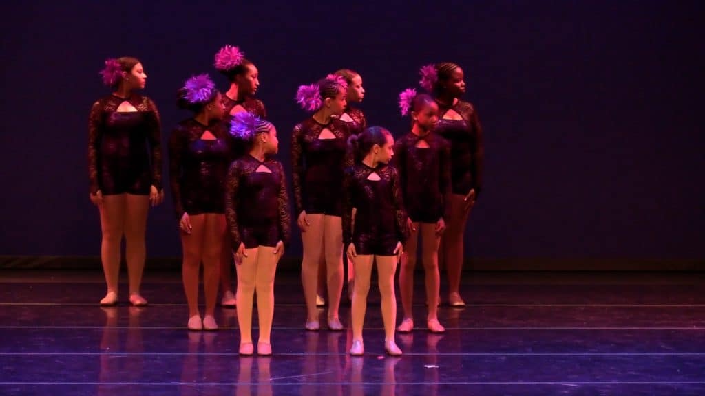 Vibrant dance performance by young girls in black lace costumes at AbunDance studio.